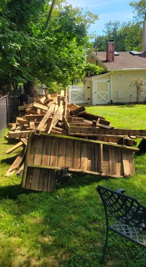 Torn-out wood deck boards piled in the backyard