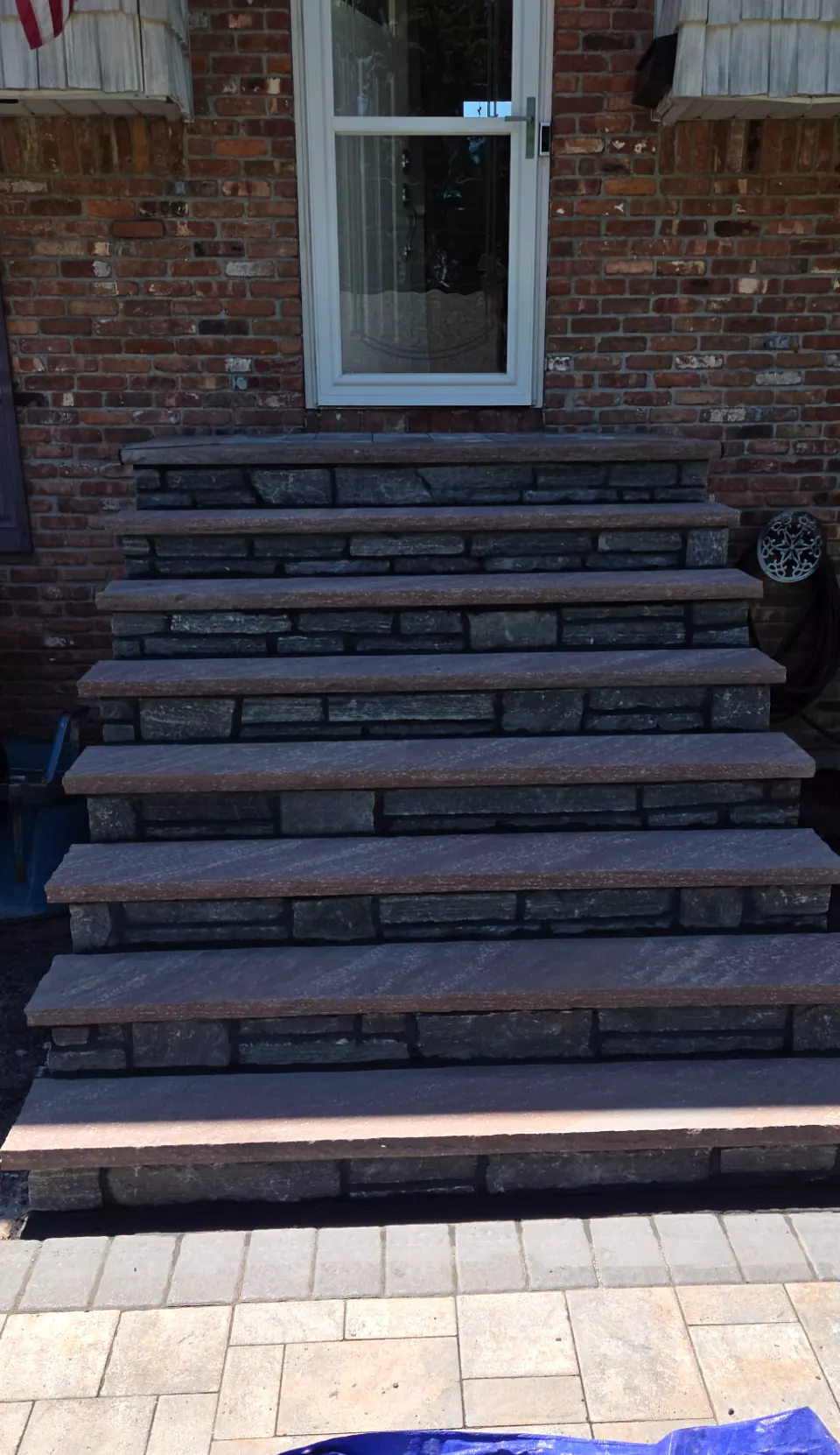 Finished front stoop with stacked stone risers and dark stone treads leading to the front door